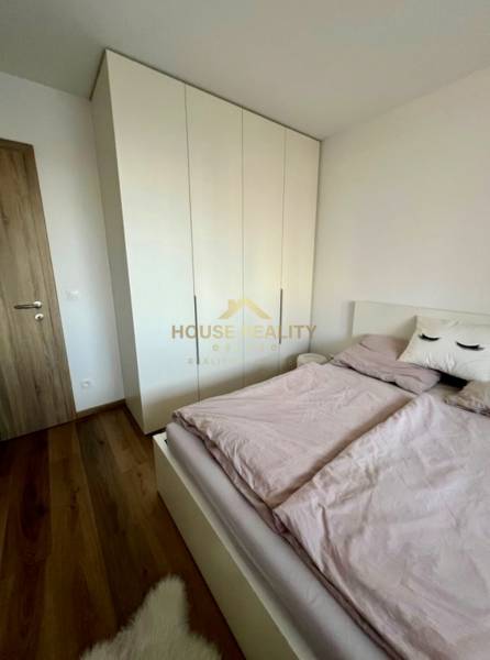 Bedroom in a 2-room apartment with a bed, wardrobe, and wooden decor flooring.