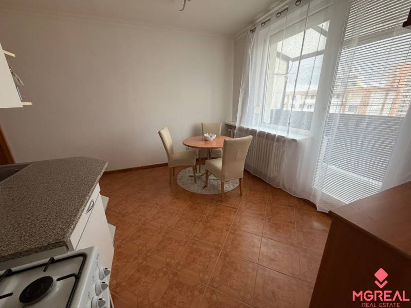 A kitchen in a 3-room apartment with a ceramic floor, table, chairs, and a large window.