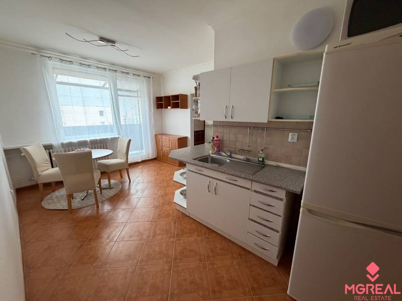 A kitchen in a 3-room apartment with a dining area and a wooden-patterned floor.