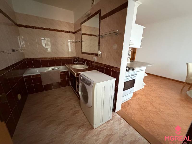Bathroom in a 3-room apartment with a bathtub, washing machine, and connection to the kitchen.