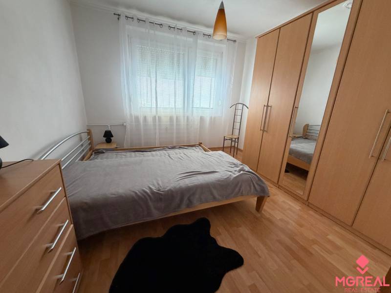 A bedroom in a 3-room apartment with a wooden decor floor and a built-in wardrobe.