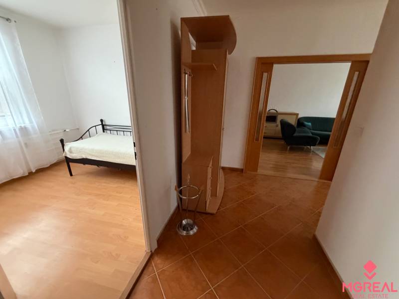 A hallway leading to the rooms in a 3-bedroom apartment with a wooden decor floor.