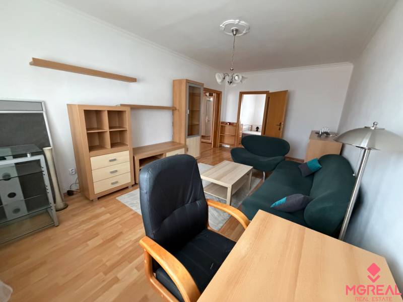 Living room in a three-room apartment with a wooden decor floor, furniture, and a sofa.