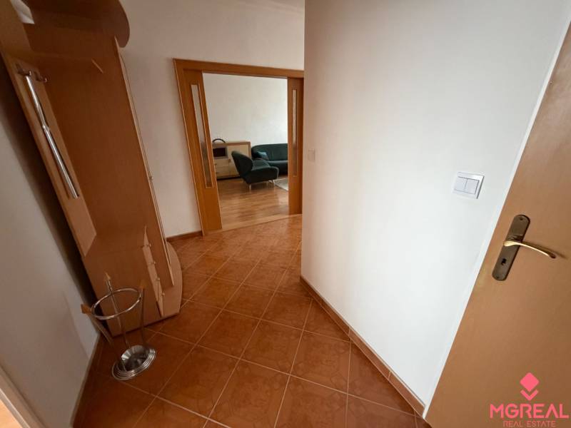 A hallway in a 3-room apartment with tiles and an entrance to the living room.
