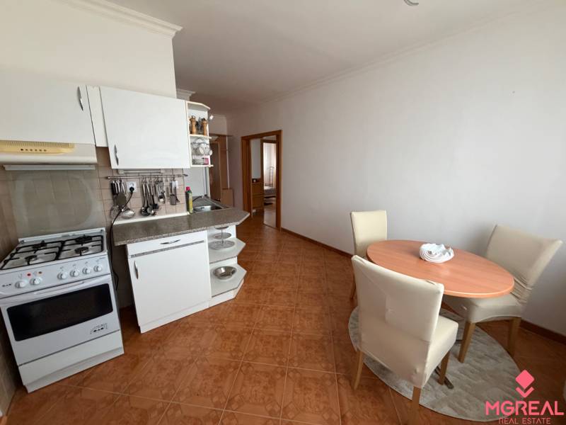 A kitchen in a 3-room apartment with a dining nook and a wooden decor floor.