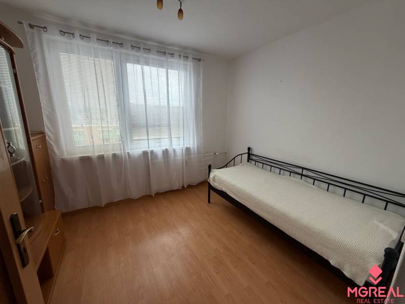 A room with a wooden floor decor and a bed in a 3-room apartment.