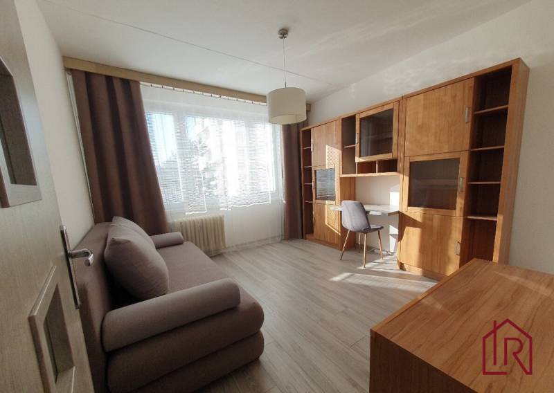 Living room in a 3-room apartment with a sofa, a desk, and a wooden decor floor.