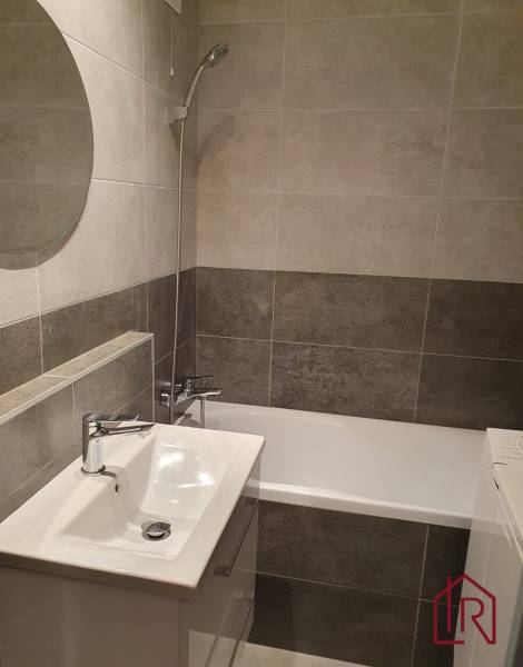 A bathroom in a 3-room apartment with a minimalist design, a bathtub, and a sink.