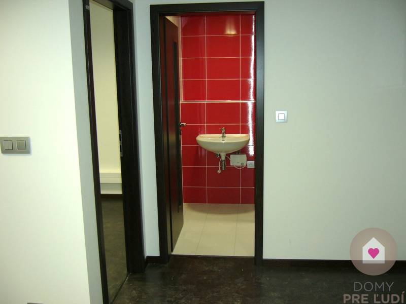 Interior of an office with white walls and red tiles behind the sink.