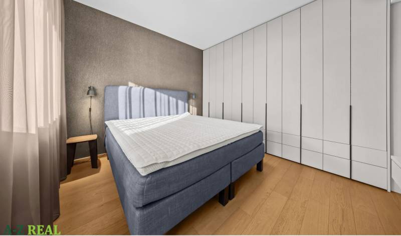 Bedroom in a 2-room apartment with a large bed, wardrobe, and wooden decor flooring.