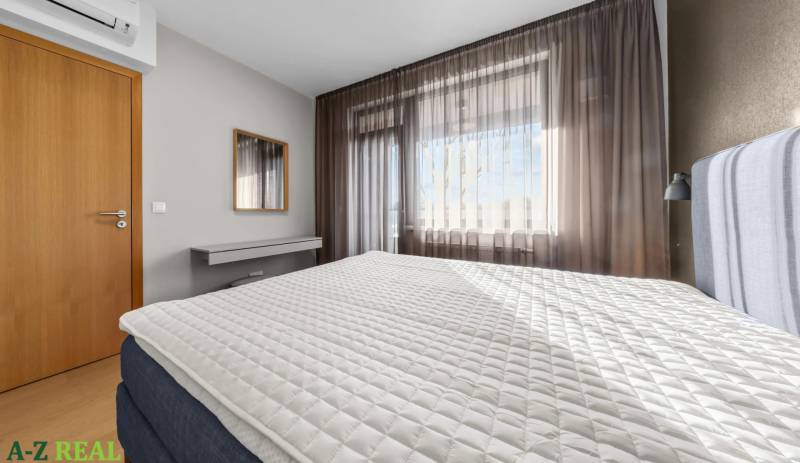 Bedroom in a 2-room apartment with a large bed, wooden doors, and a white wall.