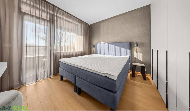 Bedroom in a 2-room apartment with a bed, wardrobes, and a floor with a wooden decor.