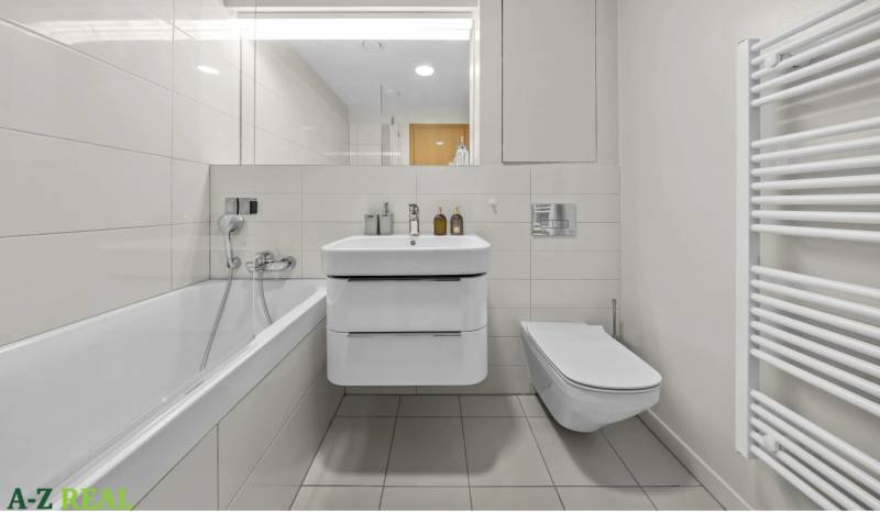 Bathroom in a 2-room apartment with a bathtub, sink, and wall-hung toilet.