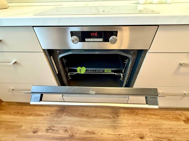 A kitchen with an oven and a wooden decor floor in a 2-room apartment.