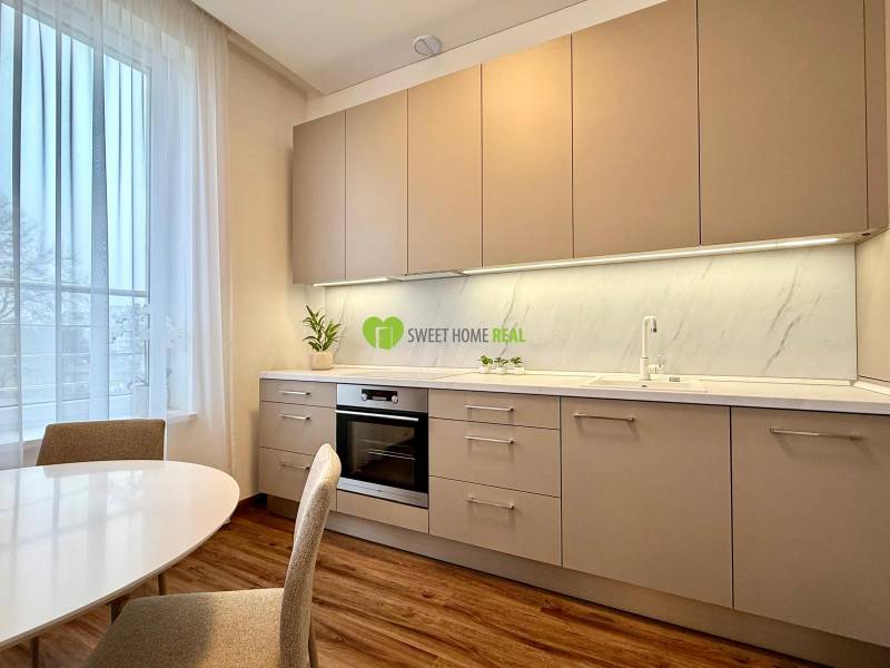 A bright kitchen with a wood-patterned floor and a dining table in a two-room apartment.