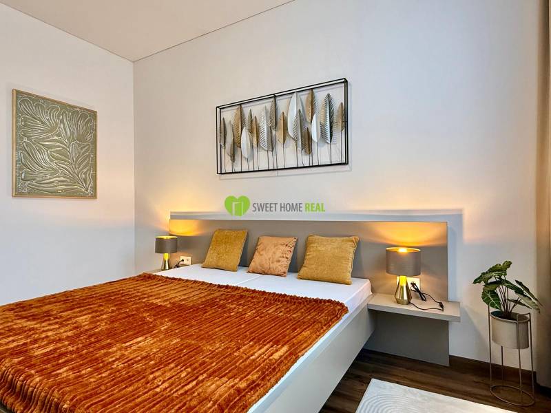 Bedroom in a 2-room apartment with a bed, decoration, and floor with wood decor.