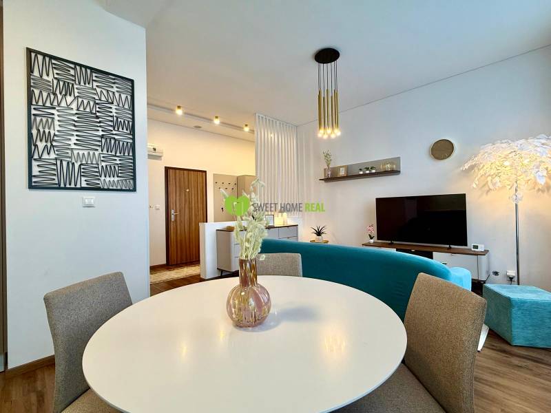 Interior of a 2-room apartment with a wooden decor floor, modern seating, and a table.