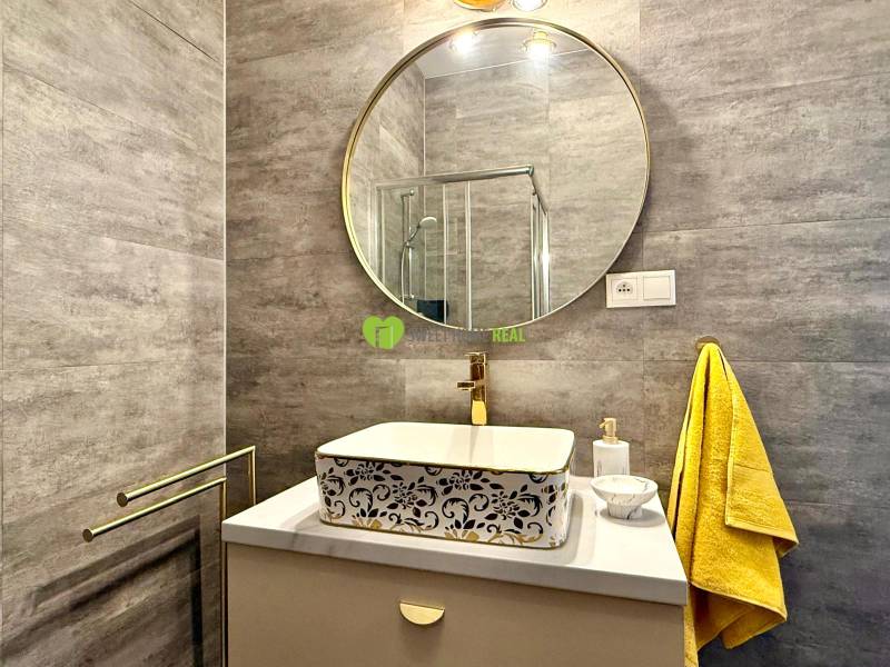 A bathroom in a 2-room apartment with a round mirror and a yellow towel.