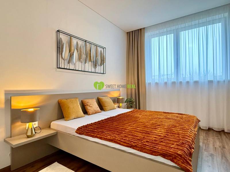 Bedroom in a 2-room apartment with a bed and a wooden decor floor.