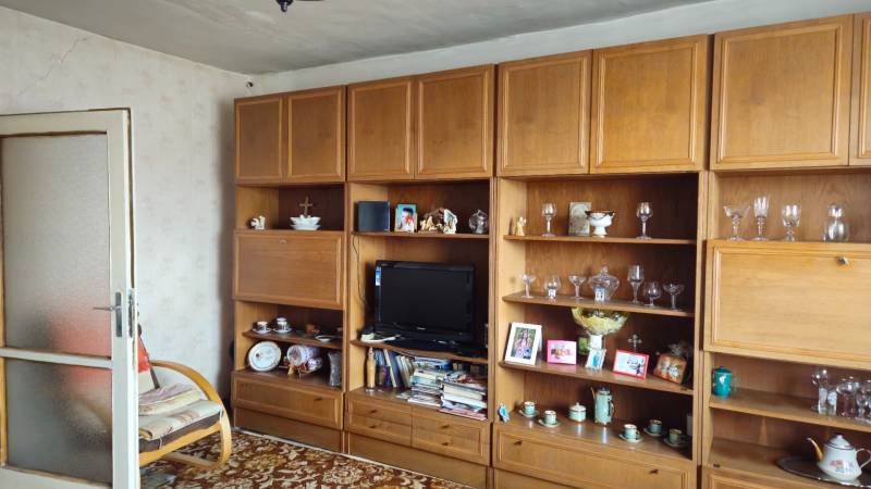 Wooden wall with display cabinets, television, and decorations in a family house.