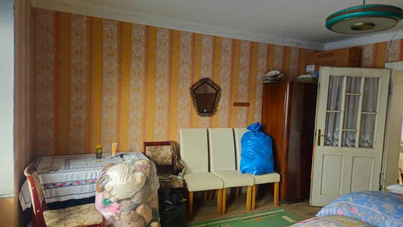 A room in a family house with retro wallpaper, furniture, and toys in plastic bags.