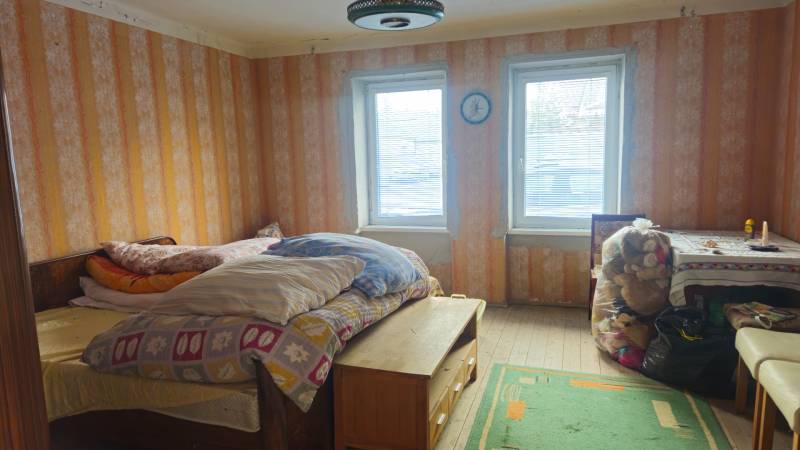 A room in a family house with a bed, a table, and toys, with wooden floor decor.