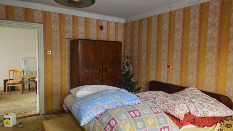 Double room in a family house with wallpaper and wooden wardrobes.