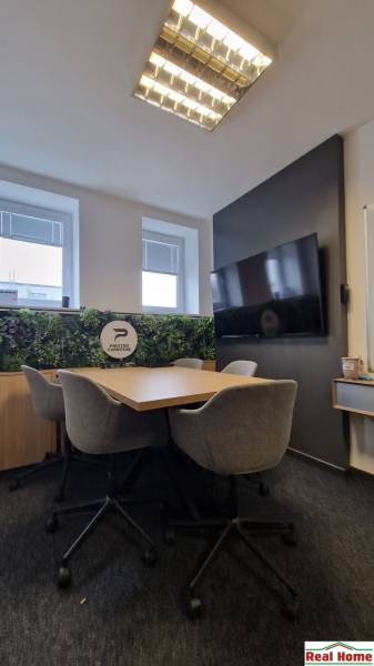 Office seating with a conference table, gray chairs, and green wall decoration.