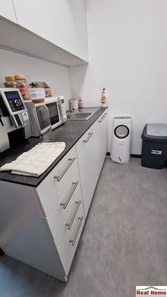 A kitchenette in the office with a microwave, sink, coffee maker, and trash bin.