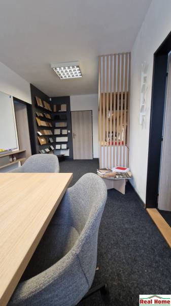 Offices with carpet flooring, a wooden desk, and a bookshelf.