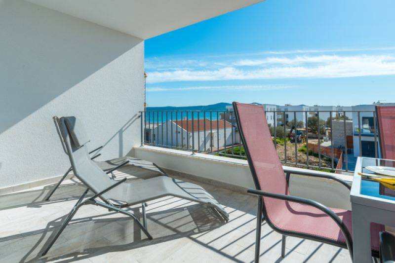 Terrace of a 3-room apartment in Sukošan with a sea view, folding chairs, clear sky.