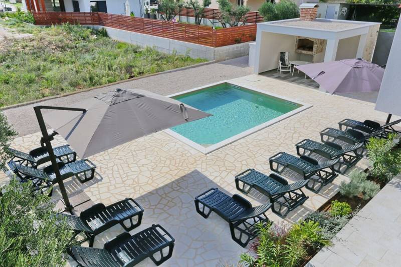 A swimming pool with loungers and umbrellas in a 3-bedroom apartment in Sukošan.
