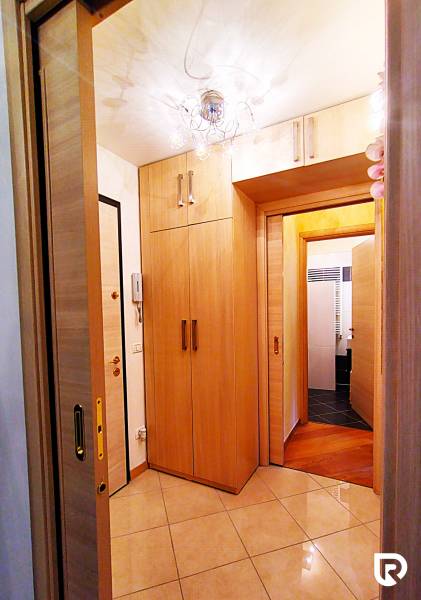 A hallway in a 2-room apartment with sliding doors and a floor with a wooden decor.