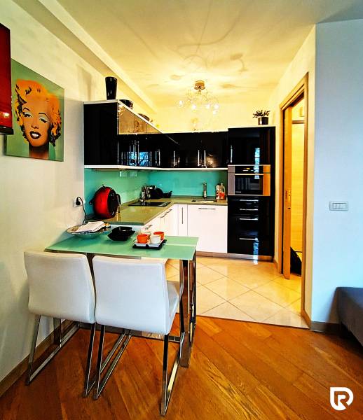 A kitchenette in a two-room apartment with a wooden decor floor and colorful walls.