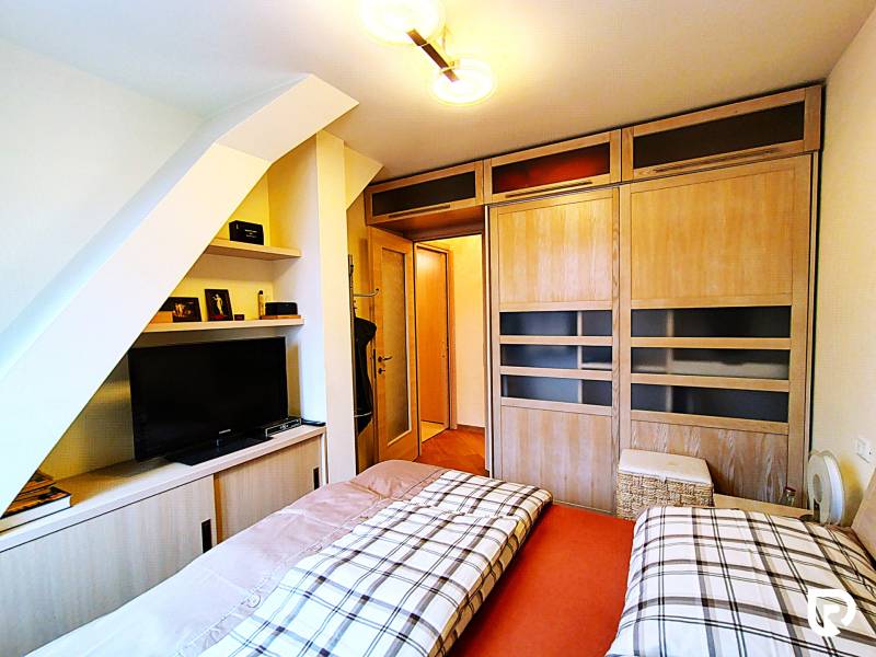 Bedroom in a 2-room apartment with sliding wardrobes and a television, floor with wood decor.