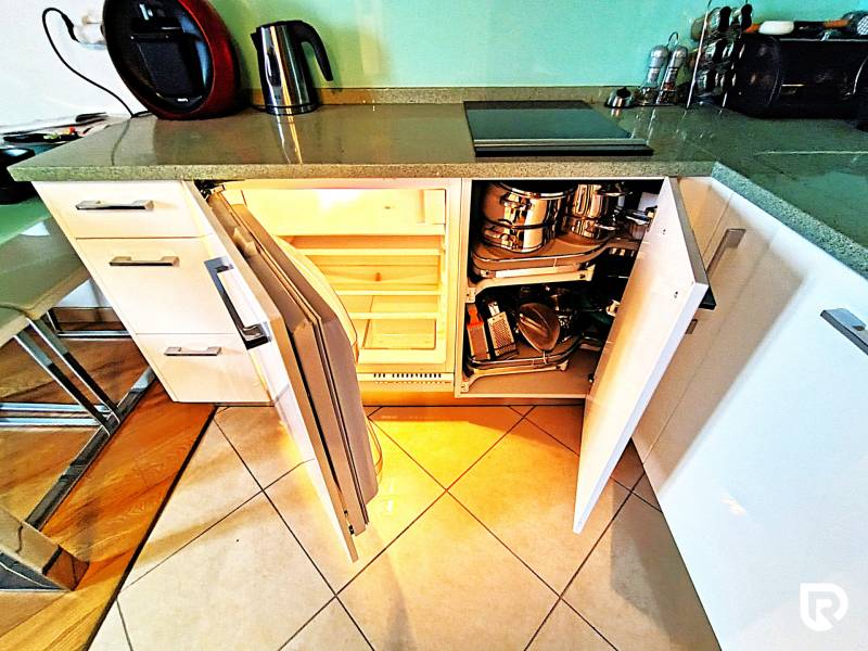 A kitchen in a 2-room apartment with open cabinets, a floor with wooden decor and tiles.