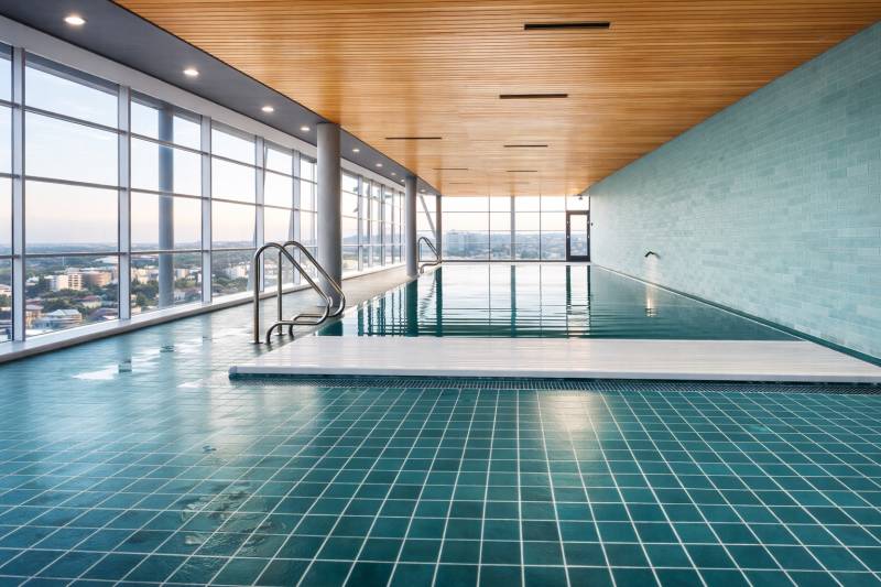 Indoor pool with large windows, city view, and wooden ceiling.