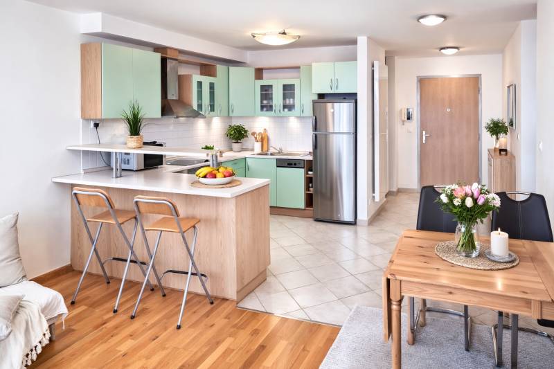 A kitchen in a 2-room apartment with a wooden decor floor and a dining table.