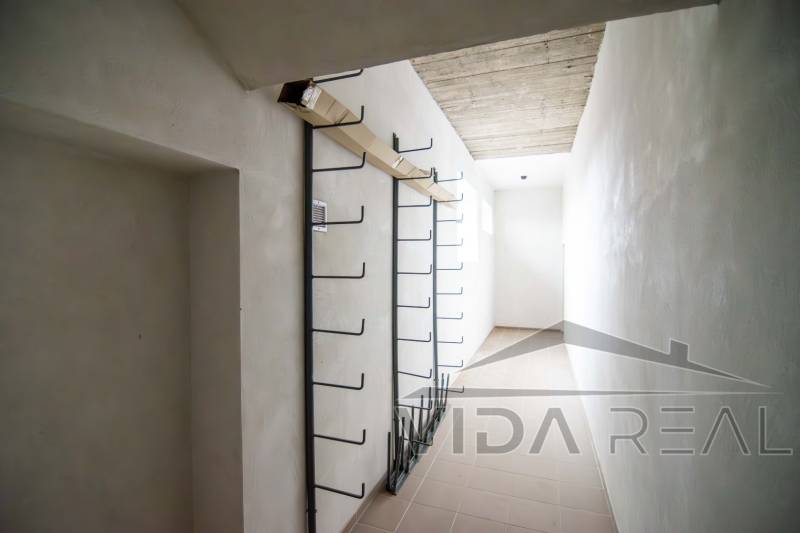 A narrow interior space in a warehouse with metal hooks on the wall.