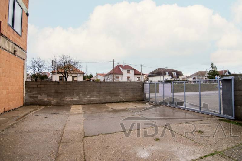 Exterior on Nádražná Street in Šenkvice, next to warehouses and halls with a steel gate.