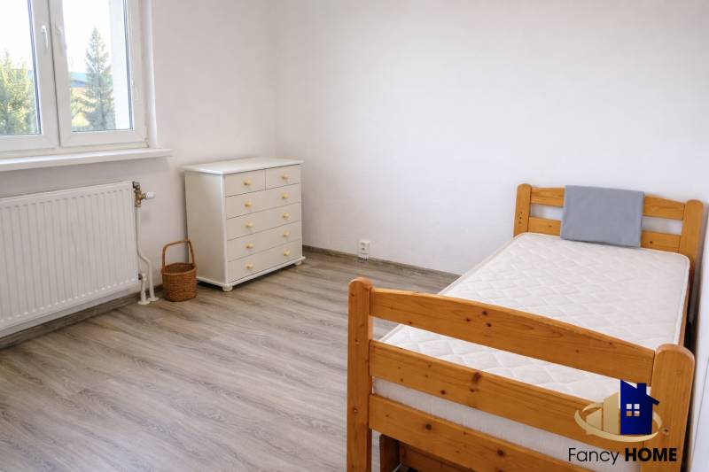 A room in a 3-room apartment with a wooden decor floor, a bed, and a dresser.