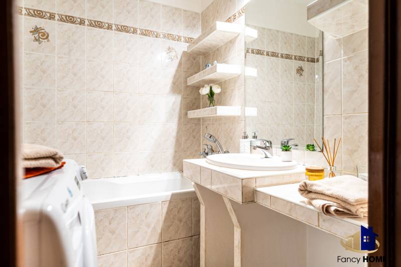 A bathroom with corners in a 3-room apartment, with a shower, sink, and washing machine.