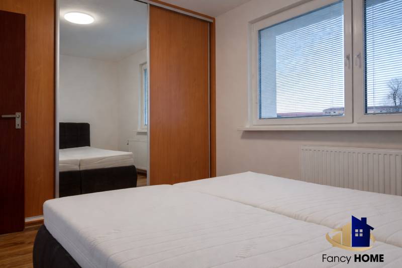 A bedroom in a 3-room apartment with a large window, built-in wardrobe, and a bed.