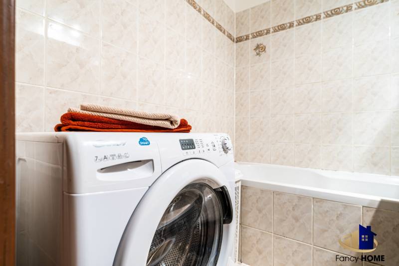 Bathroom with a washing machine in a 3-room apartment; beige tiles, stored towels.