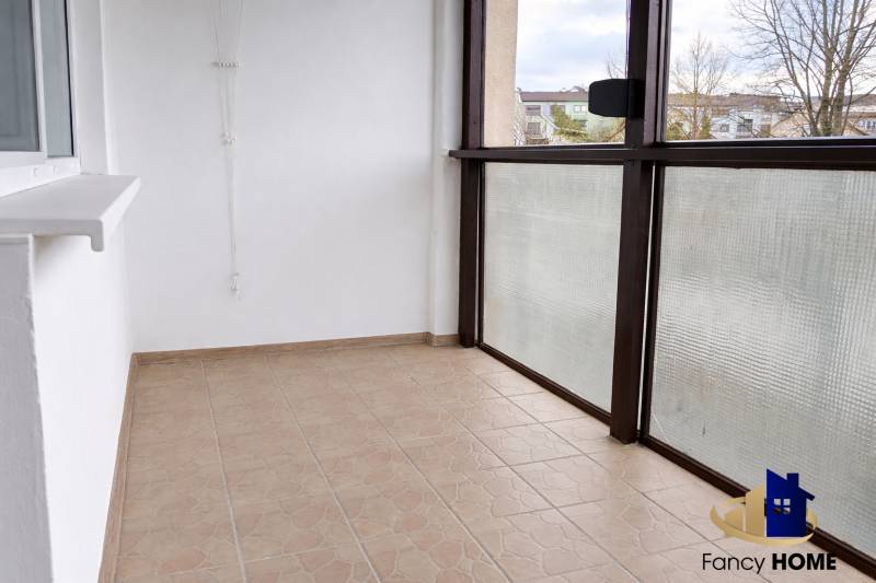 Glazed balcony of a 3-room apartment, tiled floor, view of the surroundings.