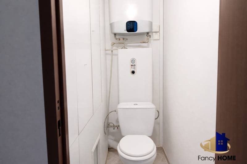 Bathroom with toilet and boiler in a 3-room apartment, light walls and simple design.