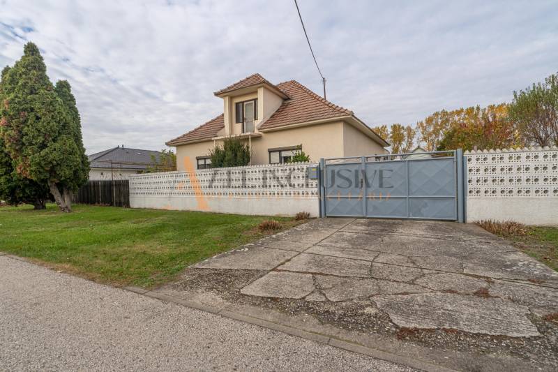 A family house in Veľké Dvorníky with a large garden, trees, and a concrete walkway.