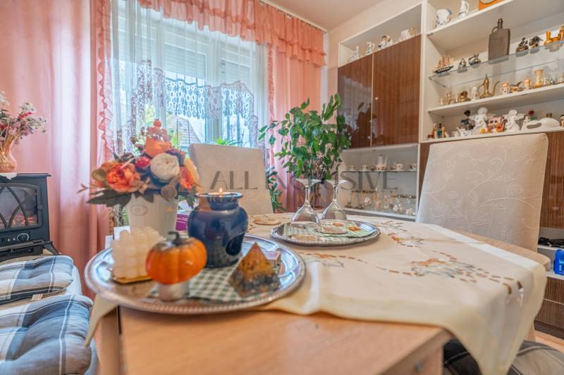 Interior of a family house with a decorated table, glass cabinet, and pink curtains.