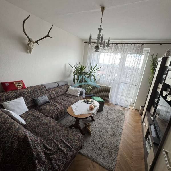 Living room in a 4-room apartment with a corner sofa and a floor with a wooden decor.