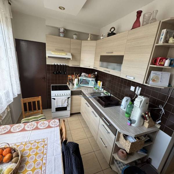 A kitchen in a 4-room apartment with a countertop, stove, wooden cabinets, and a round table.